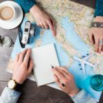 2 persons in a table with coffee, map, airplain toy and notebook